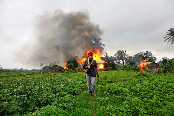 walks in front of burning houses during fighting