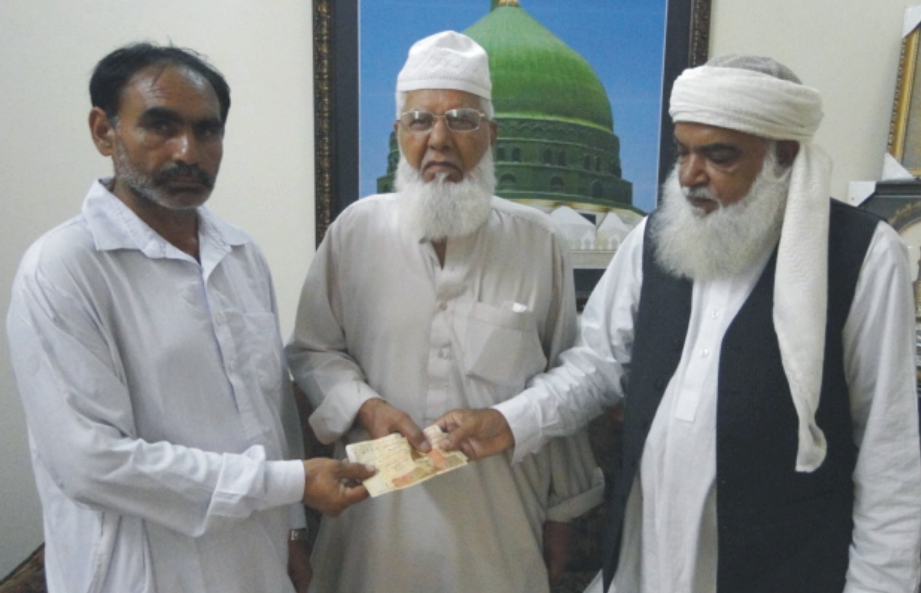 پیر محمد افضل قادری اور افضلیہ ویلفیئر فاونڈیشن یو کے کے رہنما حاجی محمد قربان مستحقین میں عیدی تقسیم کر رہے ہیں